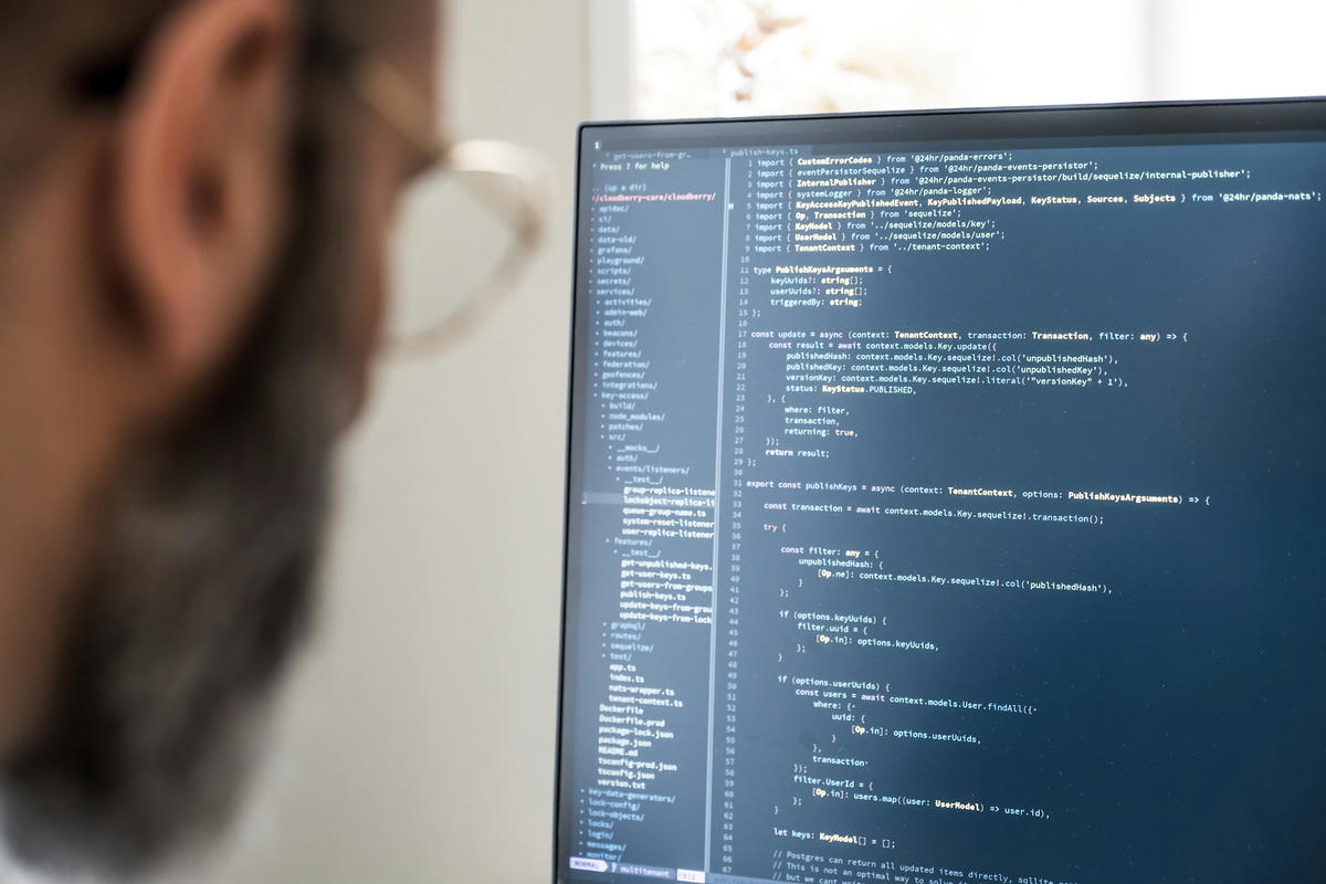 Utvecklare på TwoFour som skriver kod på en datorskärm. Skärmen visar källkod, medan utvecklarens ansikte syns suddigt i bakgrunden.